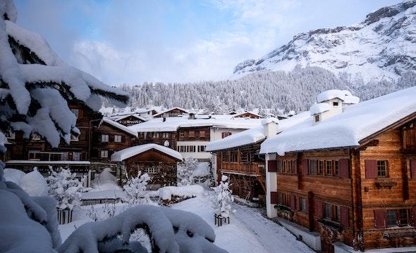 Snow covered Swiss chalets with mountain behind